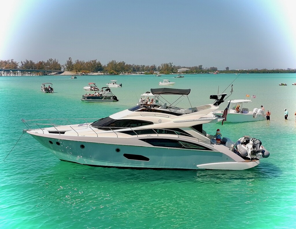 Yacht anchored at sandbar with guests swimming in crystal clear turquoise water